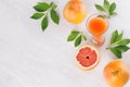 Fresh pink juice and grapefruits with green leaves on white wood board, top view, border. Royalty Free Stock Photo