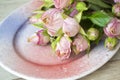 Fresh pink roses flowers on purple and pink painted ceramic plate close up. Holiday card