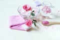 Fresh pink roses, water, petals, candles on a light background, body care products, natural home cosmetics