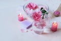 Fresh pink roses, water, petals, candles on a light background