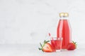 Fresh pink strawberry juice in glass bottle mock up with glass, straw, fruit slices in soft light white interior on wood tableÃÅ½