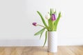 Fresh pink tulip bouquet on a shelf in front of a white wall. View with copy space Royalty Free Stock Photo