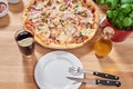 Fresh pizza with ham, hot pepper and capers and black olives on wooden table in restaurant. Royalty Free Stock Photo