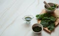 Fresh plantain leaves Plantago major in a mortar with a pestle, puree and juice from plantain on a pastel green marble backgroun