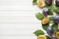 Fresh plum fruit with leaves on a light table. Royalty Free Stock Photo