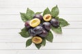 Fresh plum fruit with leaves on a light table. Royalty Free Stock Photo