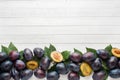 Fresh plum fruit with leaves on a light table. Royalty Free Stock Photo