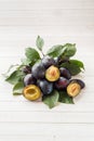 Fresh plum fruit with leaves on a light table. Royalty Free Stock Photo