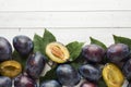 Fresh plum fruit with leaves on a light table. Royalty Free Stock Photo