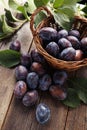 Fresh plums in basket on brown wooden background Royalty Free Stock Photo