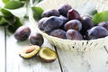 Fresh plums in basket on white wooden background Royalty Free Stock Photo