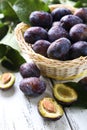 Fresh plums in basket on white wooden background Royalty Free Stock Photo