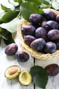 Fresh plums in basket on white wooden background Royalty Free Stock Photo