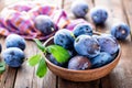 Fresh plums with green leaves on wooden rustic background Royalty Free Stock Photo