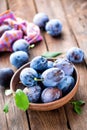 Fresh plums with green leaves on wooden rustic background Royalty Free Stock Photo