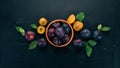 Fresh plums with leaves. Fruits. On a black wooden background. Top view. Royalty Free Stock Photo