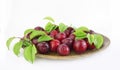 Fresh plums with leaves on a wooden plate close-up. Copy space Royalty Free Stock Photo