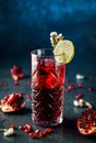 Fresh pomegranate cocktail with lime in drink glass on dark blue background. Studio shot of drink in freeze motion, splash and Royalty Free Stock Photo