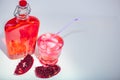 Freshly made Pomegranate Juice with full bottle and glass with straw.