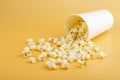 Fresh popcorn spilled out of thewhite box on a orange background. Cinema snack concept. The food for watching a movie and