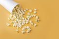 Fresh popcorn spilled out of the white box on a orange background. Cinema