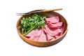 Fresh pork ham slices in wooden plate with arugula salad. Isolated on white background. Top view. Royalty Free Stock Photo