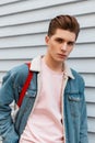 Fresh portrait European young man in vogue pink sweatshirt in fashionable blue denim jacket with fabric bag near vintage white Royalty Free Stock Photo