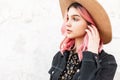 Fresh portrait fashionable young woman with pink amazing hair in stylish straw hat in denim trendy jacket near white vintage wall Royalty Free Stock Photo