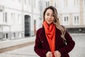 Fresh portrait young woman in vintage burgundy coat with fashionable orange scarf on street in city. Pretty beautiful girl model Royalty Free Stock Photo