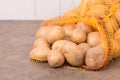 Fresh potatoes in a net on a brown textured background Royalty Free Stock Photo