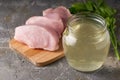 Fresh poultry broth in a glass jar on a table with vegetables and pieces of fresh poultry meat Royalty Free Stock Photo