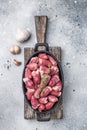 Fresh poultry duck hearts in a cast iron pan, enhanced with garlic and herbs, set against a textured grey backdrop. Royalty Free Stock Photo