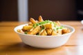 fresh poutine in a white bowl, cheese curds melting