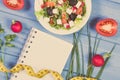 Fresh greek salad with feta cheese and tape measure with notepad for notes. Slimming and healthy nutrition Royalty Free Stock Photo