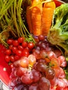Fresh produce - carrots broccoli cherry tomatoes and grapes - closeup in a red colander
