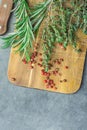 Fresh Provence Herbs Rosemary Thyme Twigs red Pink Peppers on Aged Wood Cutting Board Knife on Dark Concrete Stone Table. Top View