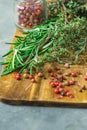 Fresh Provence Herbs Rosemary Thyme Twigs red Pink Peppers in Glass Jar on Aged Wood Cutting Board Knife on Dark Table