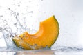 Fresh pumpkin slice splashing into water with dynamic droplets