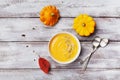 Fresh pumpkin soup decorated seeds and thyme in white bowl on rustic wooden table top view. Cozy lifestyle shot for autumn menu.