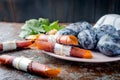 Fresh Purple Plums in a ceramic plate and scattered on the table, plums in the form of dry chips and fruit leather rolls on dark Royalty Free Stock Photo