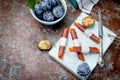 Fresh Purple Plums in a pottery blue bowl and scattered on the table, plums in the form of dry chips and fruit leather rolls on Royalty Free Stock Photo