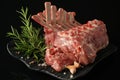 Fresh rack of lamb on a black plate on a dark background with spices: rosemary, pepper, salt Royalty Free Stock Photo