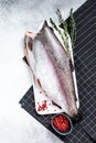 Fresh rainbow trout fish marinated with salt and thyme. Gray background. Top view