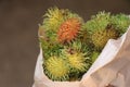 Fresh Rambutan fruit in a small paper bag, Close up view of ripe and unripe rambootan fruit Royalty Free Stock Photo