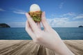 Fresh Rambutan fruit in woman hand holding peeled rambutan with a perspective wooden table over blurred sea and blue sky Royalty Free Stock Photo