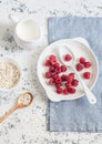 Fresh raspberries, cream and oats on a light background, top view. Delicious breakfast or snack