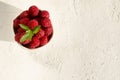 Top view of heap of delicious raspberries on the white surface, natural light.Empty space for text