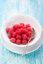 Fresh raspberries in a white ceramic bowl with metal spoon Royalty Free Stock Photo