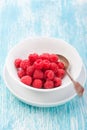 Fresh raspberries in a white ceramic bowl with metal spoon Royalty Free Stock Photo