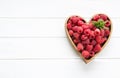 Fresh Raspberries in the wooden  plate white wooden board. Heart shape berries Royalty Free Stock Photo